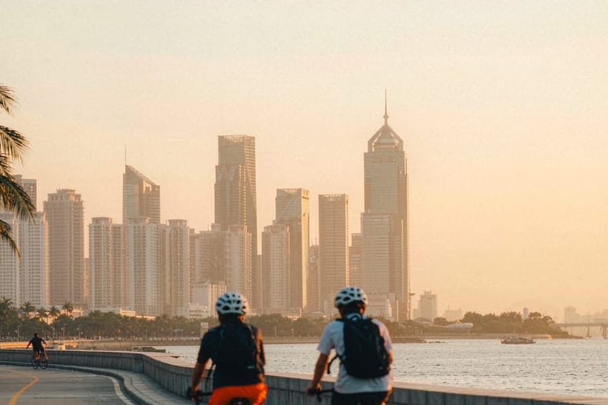 Ciclistas em orla de Shenzhen no fim da tarde